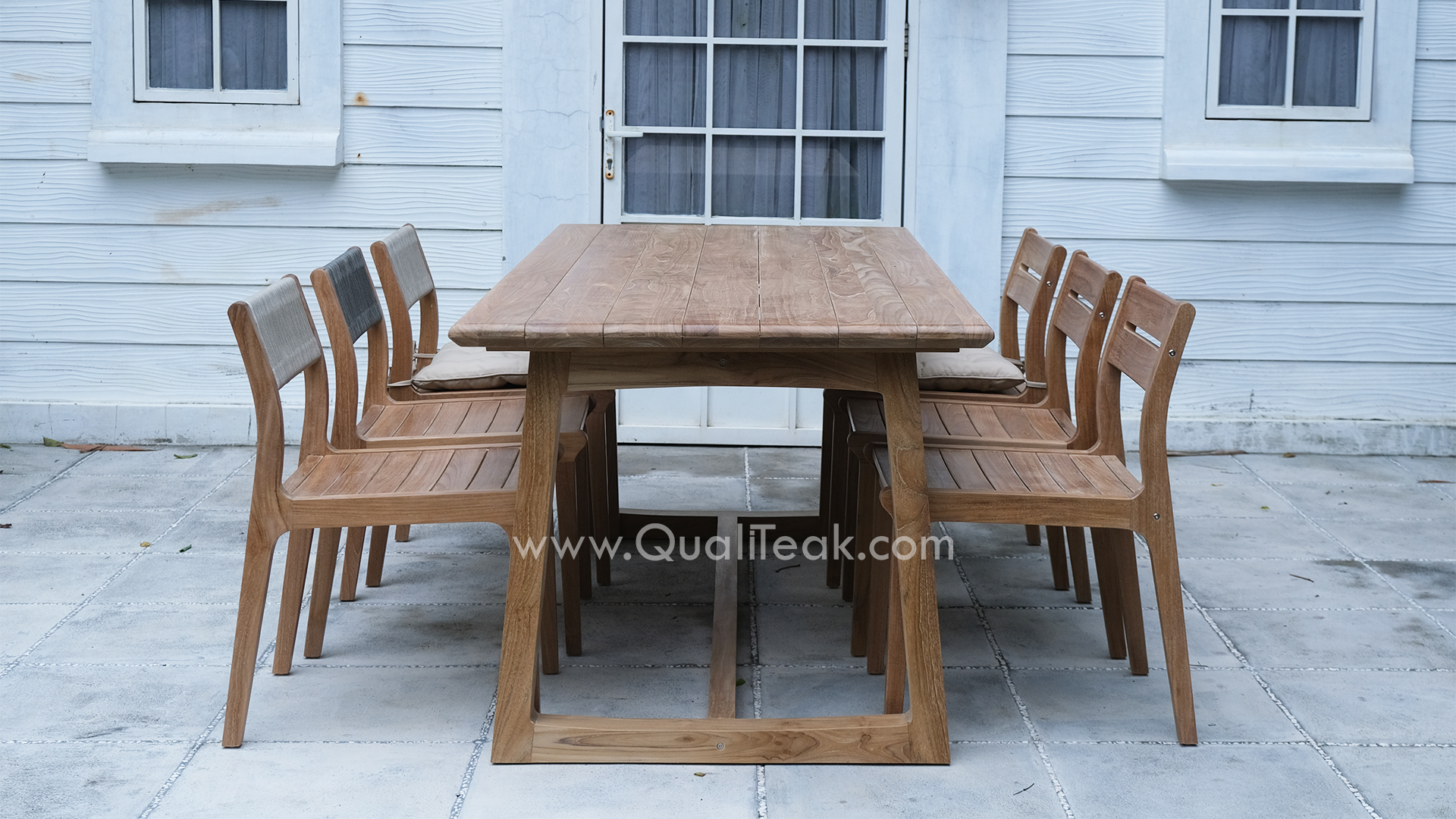 A commercial outdoor dining set featuring the Fuego teak armchairsteak armchairs tucked neatly under a rectangular teak table